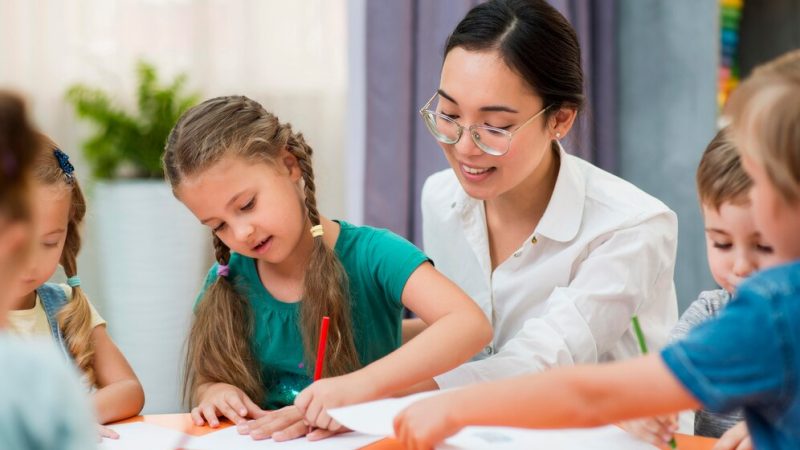 joven-profesora-ayudando-sus-alumnos-clase_23-2148633379